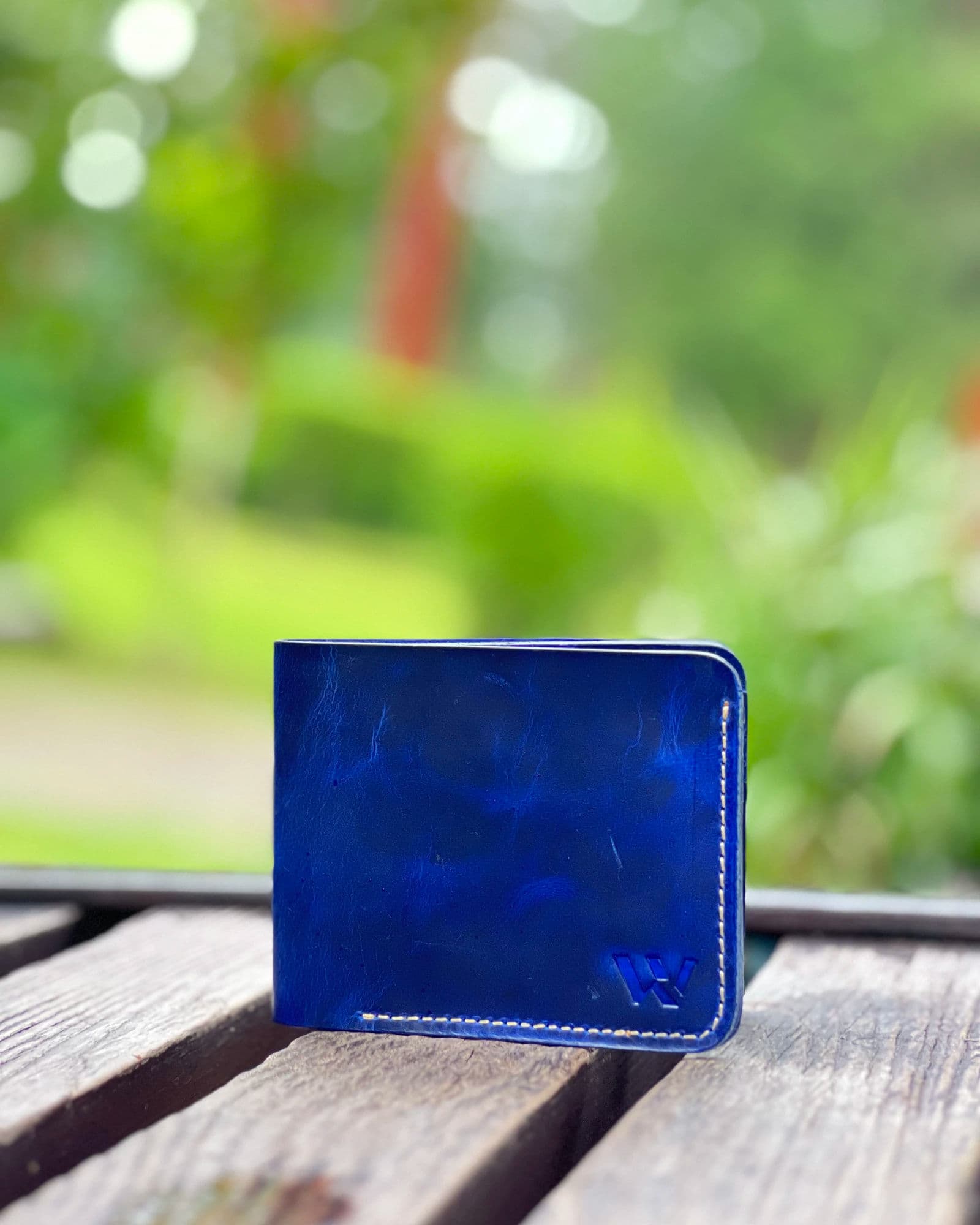 Blue slim leather bifold wallet for men with cream stitching and embossed W logo by Wrenza